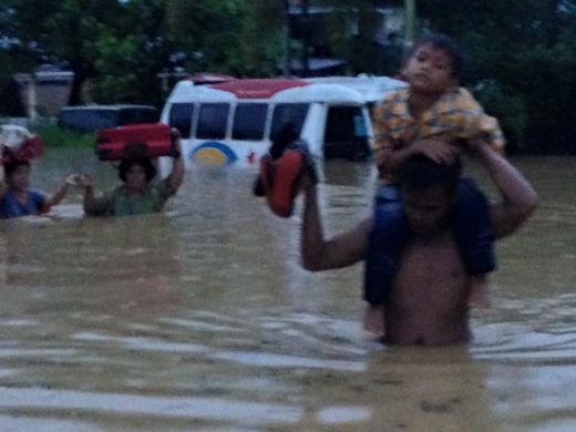 Seorang bapak panggul anak mengungsi akibat banjir.
